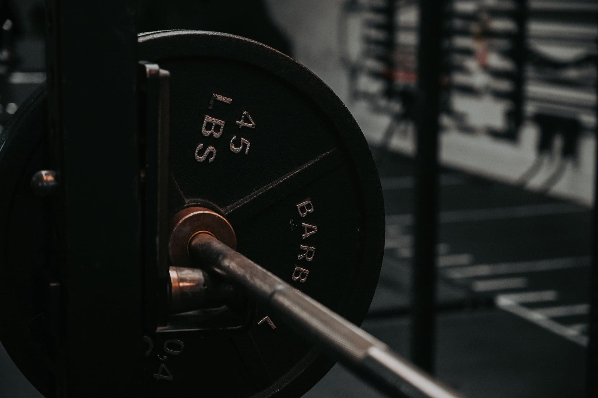 A loaded Olympic barbell on a rack in a dimly lit gym